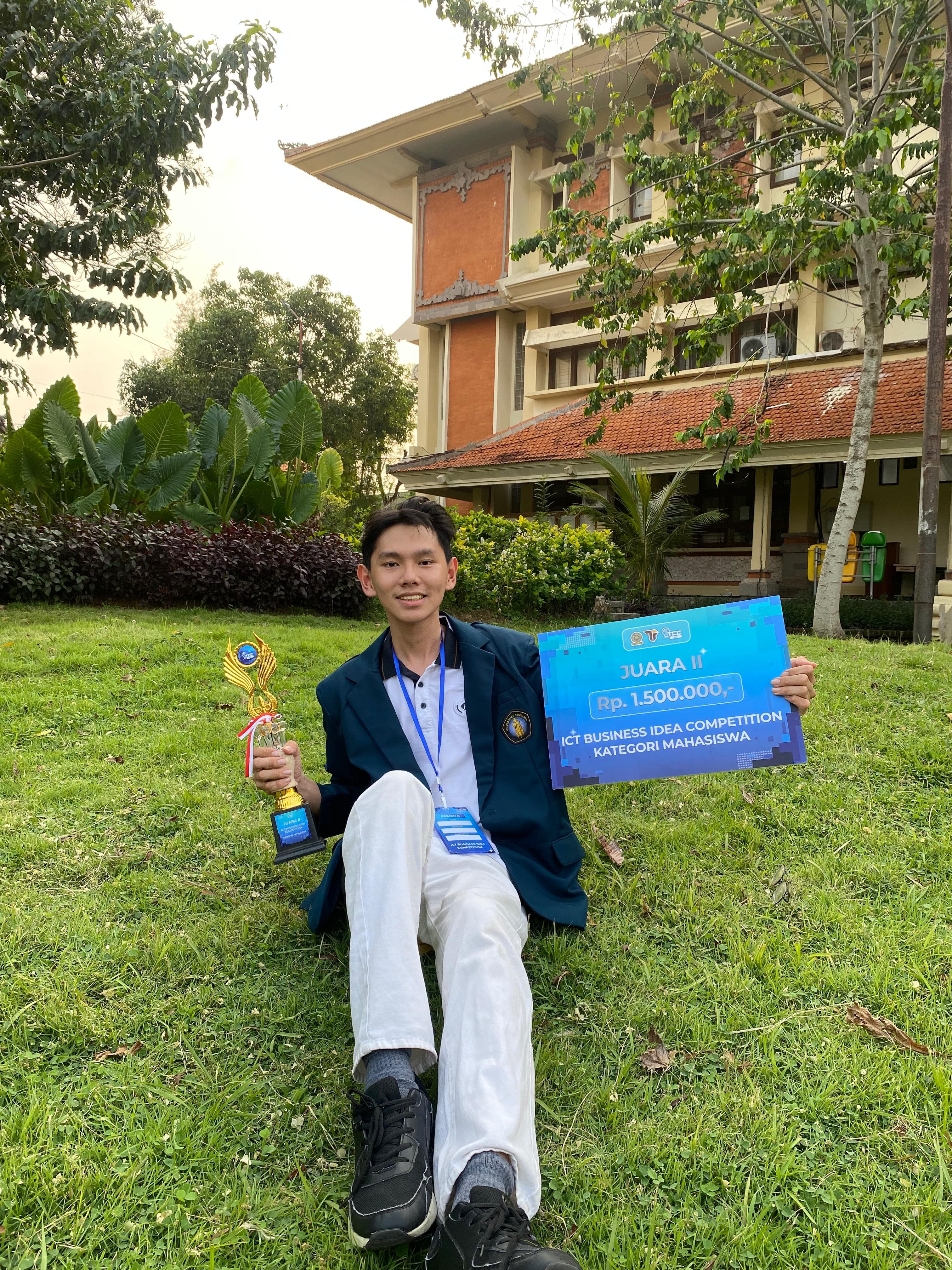 Richard holding an ICT business competition award outdoors